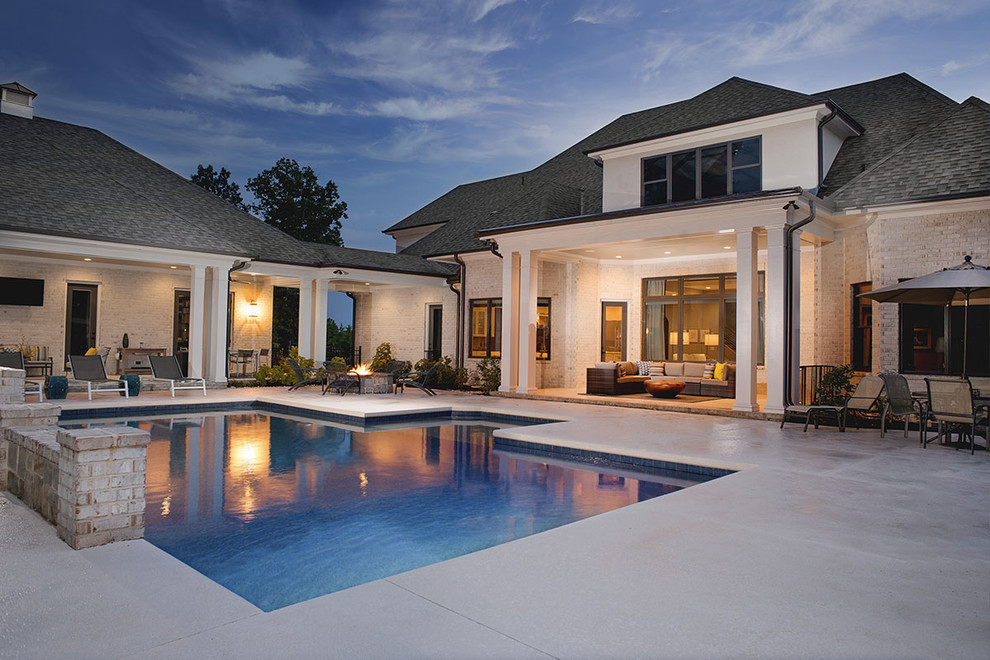 Modelo de piscina alargada contemporánea de tamaño medio rectangular en patio trasero con losas de hormigón