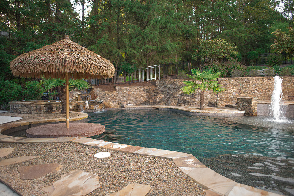 Immagine di una grande piscina tropicale personalizzata dietro casa con fontane e ghiaia