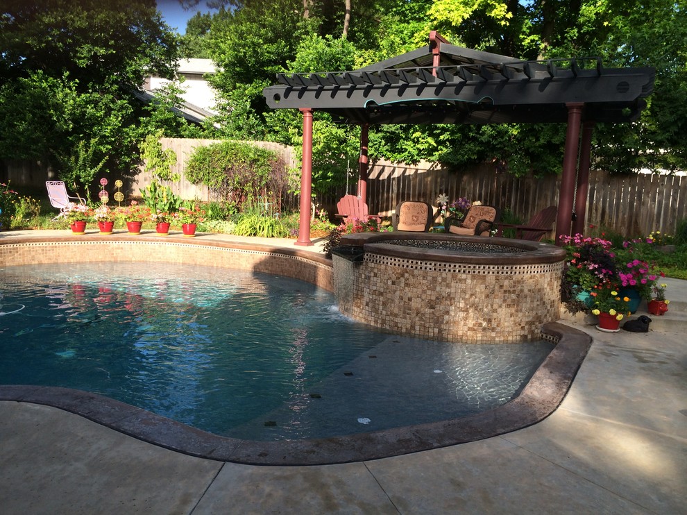 Пример оригинального дизайна: естественный бассейн среднего размера, в форме фасоли на заднем дворе в стиле неоклассика (современная классика) с джакузи и покрытием из декоративного бетона