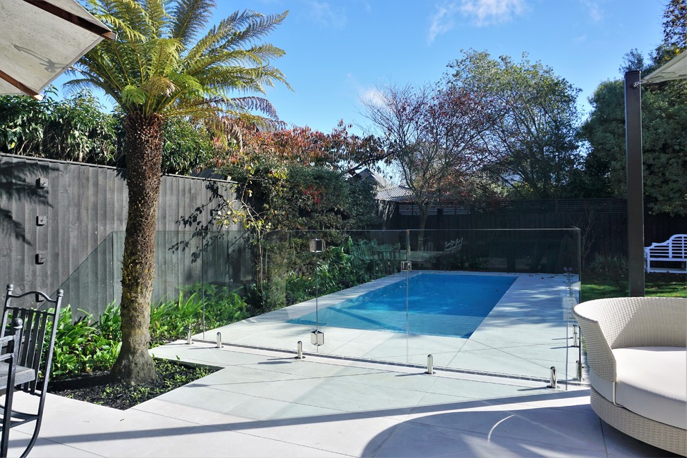 Immagine di una piscina minimalista di medie dimensioni e dietro casa con pavimentazioni in pietra naturale