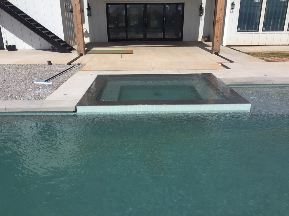 Immagine di una grande piscina monocorsia moderna personalizzata dietro casa con una vasca idromassaggio e lastre di cemento