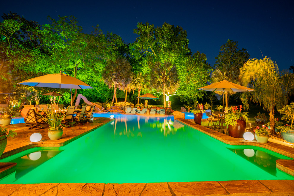 Ejemplo de casa de la piscina y piscina tropical extra grande a medida en patio trasero con suelo de baldosas