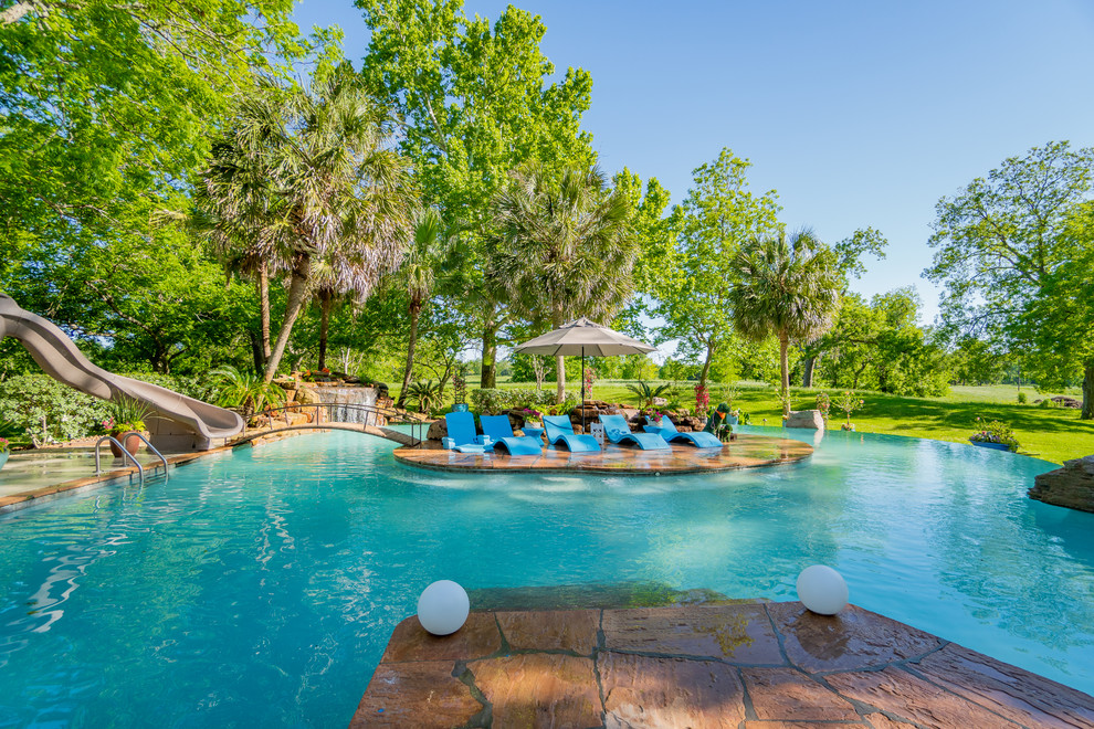 Imagen de casa de la piscina y piscina tropical extra grande a medida en patio trasero con suelo de baldosas