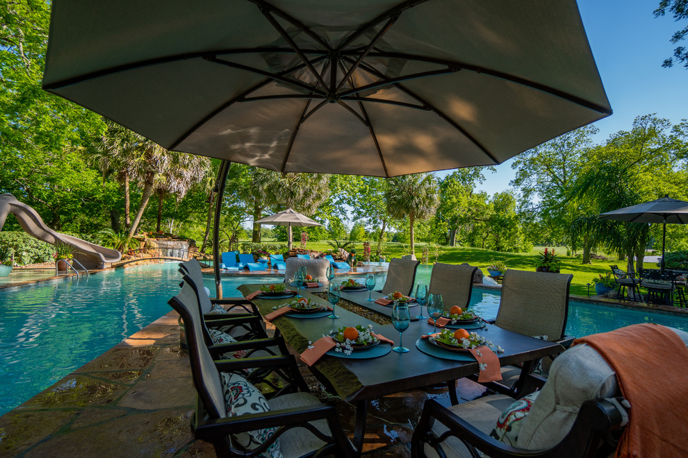 Immagine di un'ampia piscina tropicale personalizzata dietro casa con una dépendance a bordo piscina e piastrelle