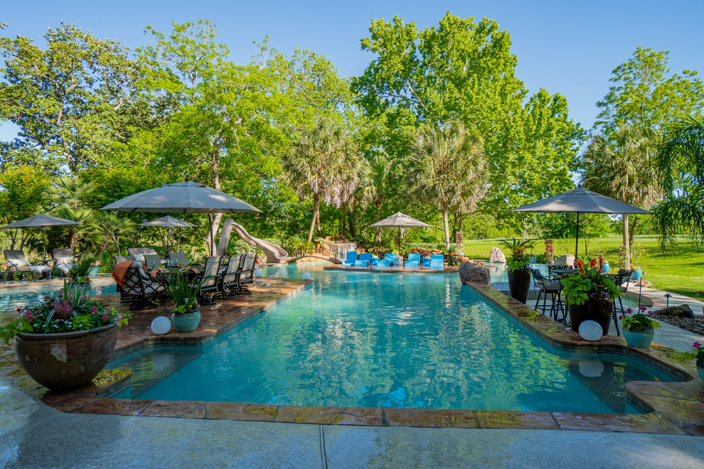Foto de casa de la piscina y piscina tropical extra grande a medida en patio trasero con suelo de baldosas