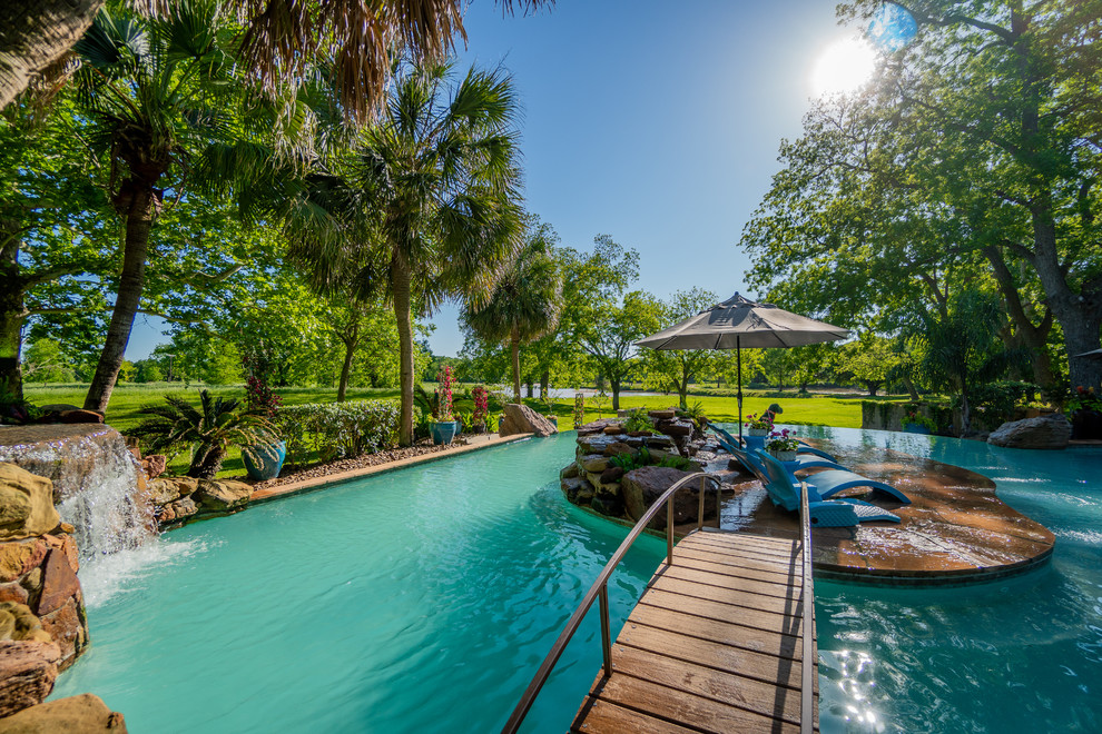 Ejemplo de casa de la piscina y piscina exótica extra grande a medida en patio trasero con suelo de baldosas