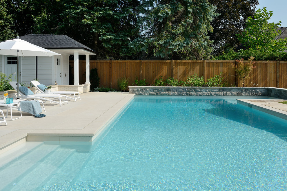 Foto de piscina alargada contemporánea grande rectangular en patio trasero con losas de hormigón