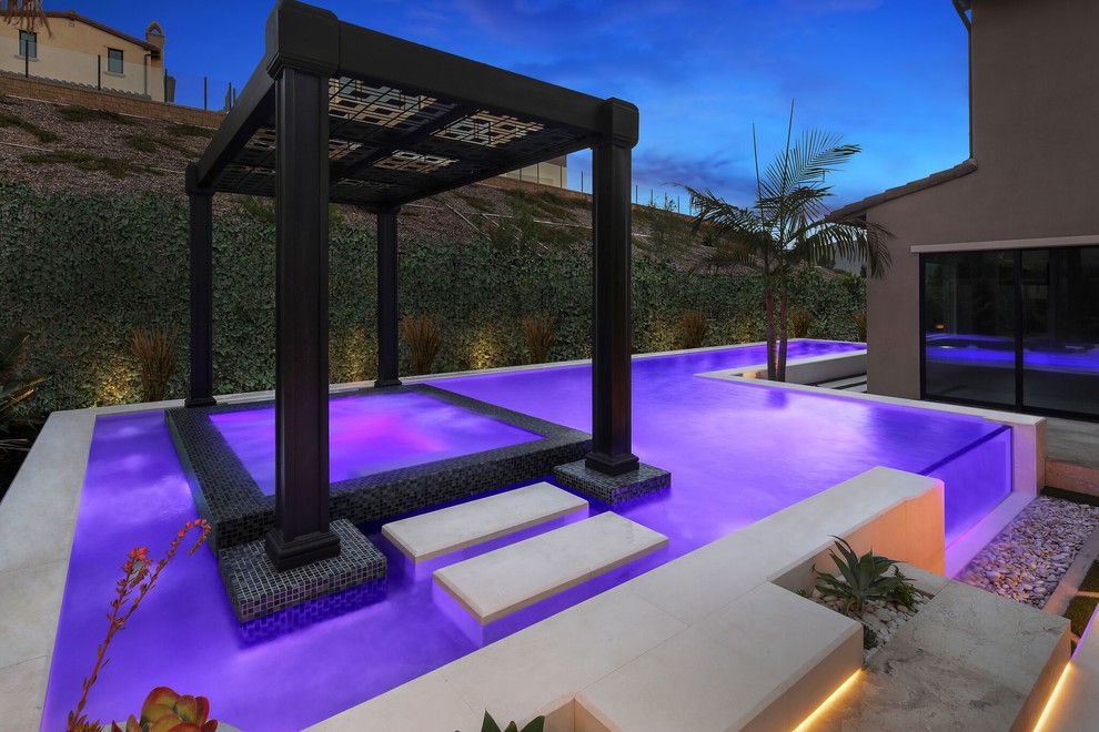 Esempio di una piccola piscina a sfioro infinito personalizzata dietro casa con una vasca idromassaggio