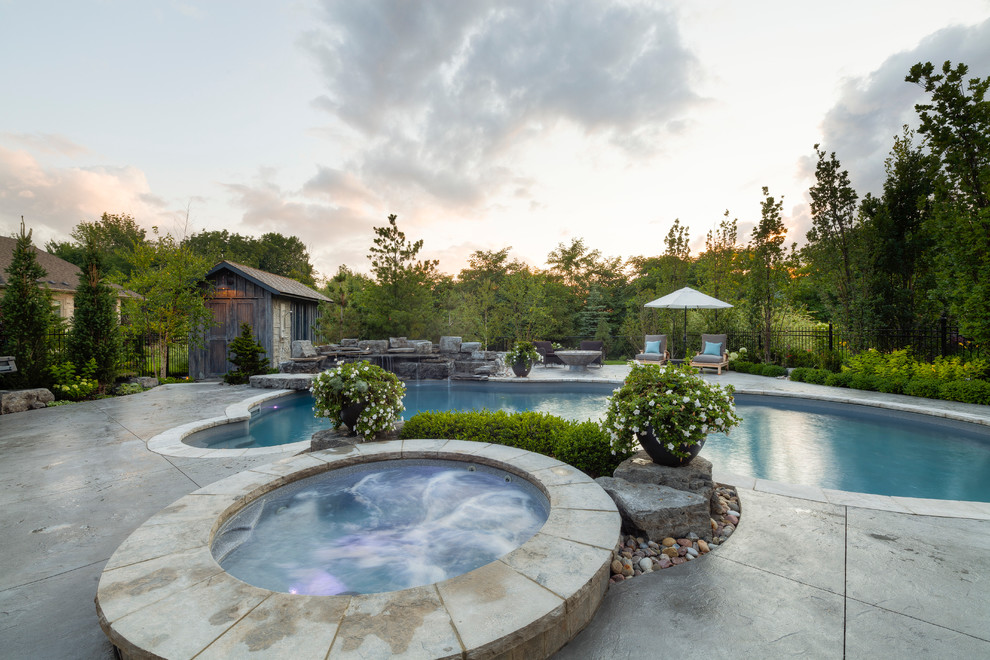Diseño de piscinas y jacuzzis alargados rurales grandes a medida en patio trasero con adoquines de hormigón