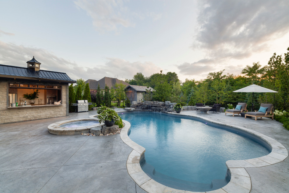 Idee per una grande piscina monocorsia stile rurale personalizzata dietro casa con una vasca idromassaggio e pavimentazioni in cemento