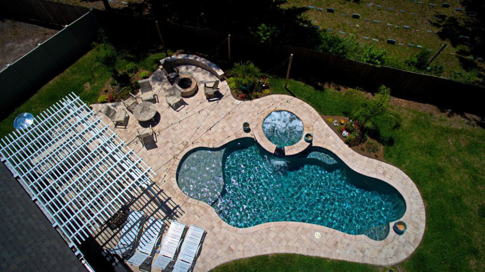 Exempel på en exotisk anpassad pool på baksidan av huset, med spabad