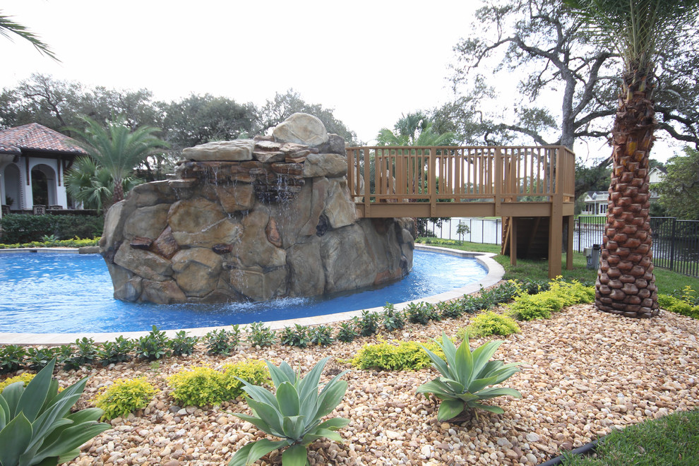 Ejemplo de piscina con fuente costera extra grande a medida en patio trasero con adoquines de piedra natural