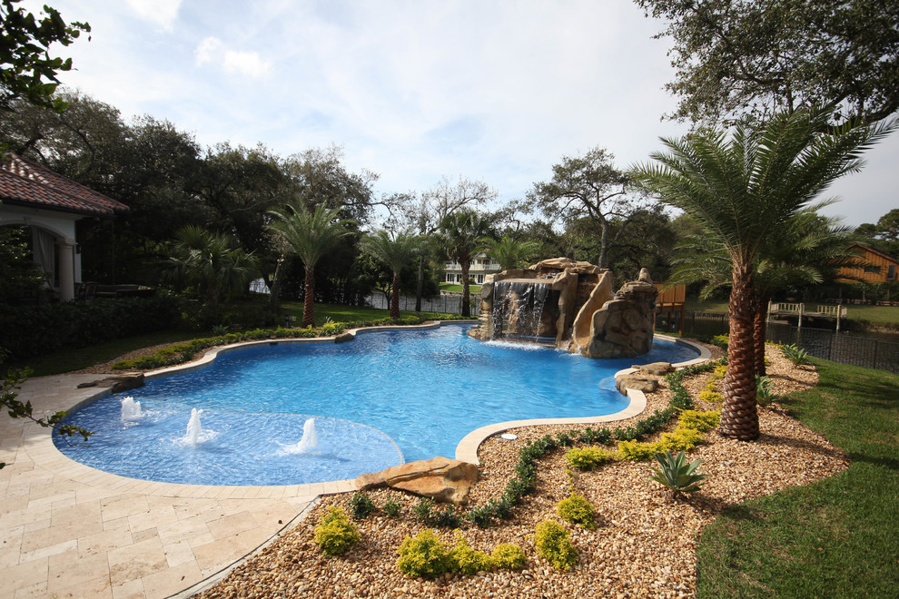 This is an example of an expansive nautical back custom shaped swimming pool in Miami with a water feature and natural stone paving.
