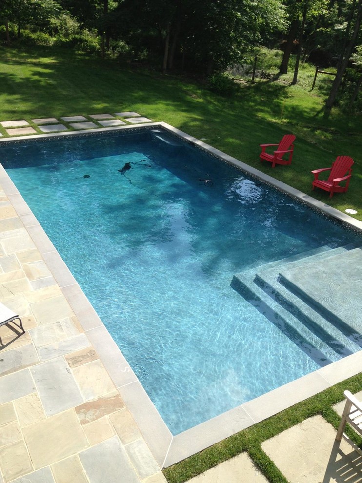 Example of a mid-sized mountain style backyard stone and rectangular pool design in New York