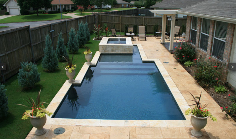 Modern inredning av en anpassad pool på baksidan av huset, med en fontän och stämplad betong