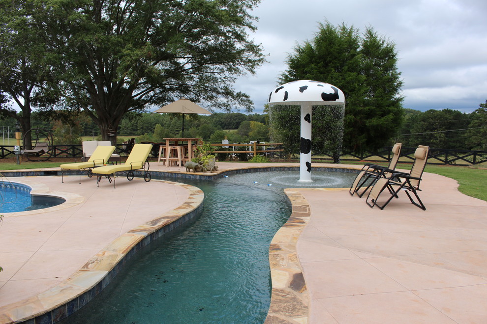 Esempio di un'ampia piscina country personalizzata dietro casa con fontane