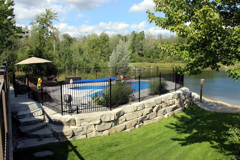 Immagine di una grande piscina monocorsia stile marino dietro casa con fontane e cemento stampato