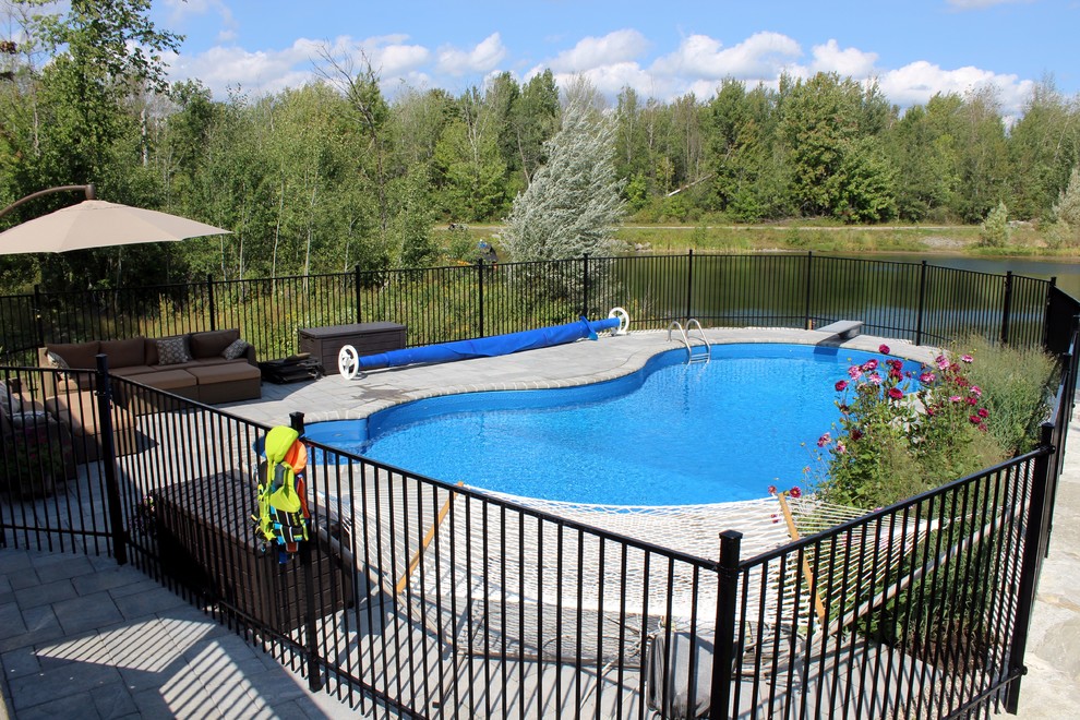 Ejemplo de piscina con fuente alargada marinera grande en patio trasero con suelo de hormigón estampado