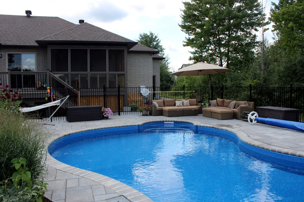 Inspiration for a large beach style back lengths swimming pool in Ottawa with a water feature and stamped concrete.