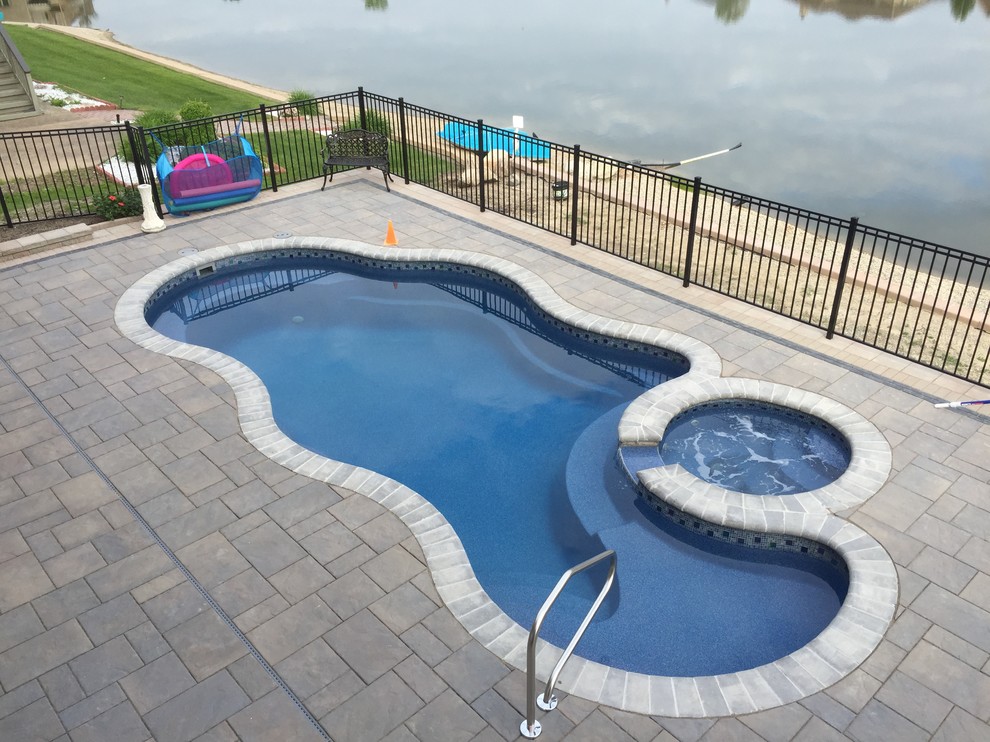 Idee per una piscina chic personalizzata dietro casa con una vasca idromassaggio e pavimentazioni in mattoni