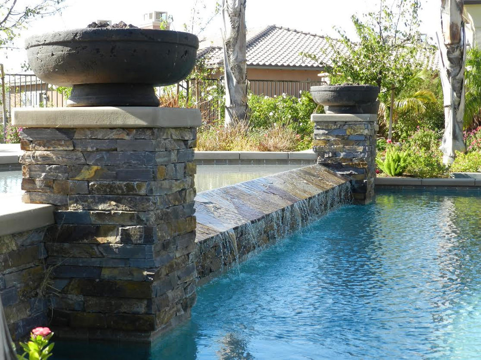Modelo de piscinas y jacuzzis alargados clásicos renovados de tamaño medio a medida en patio trasero con adoquines de hormigón