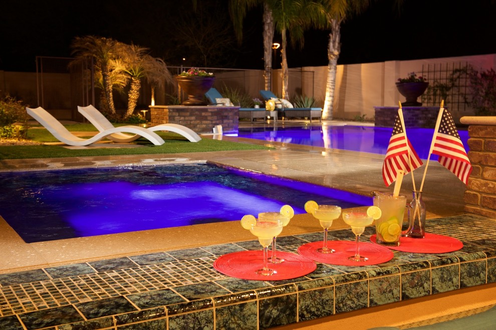 На фото: большой прямоугольный бассейн-инфинити на заднем дворе в современном стиле с домиком у бассейна и покрытием из каменной брусчатки с