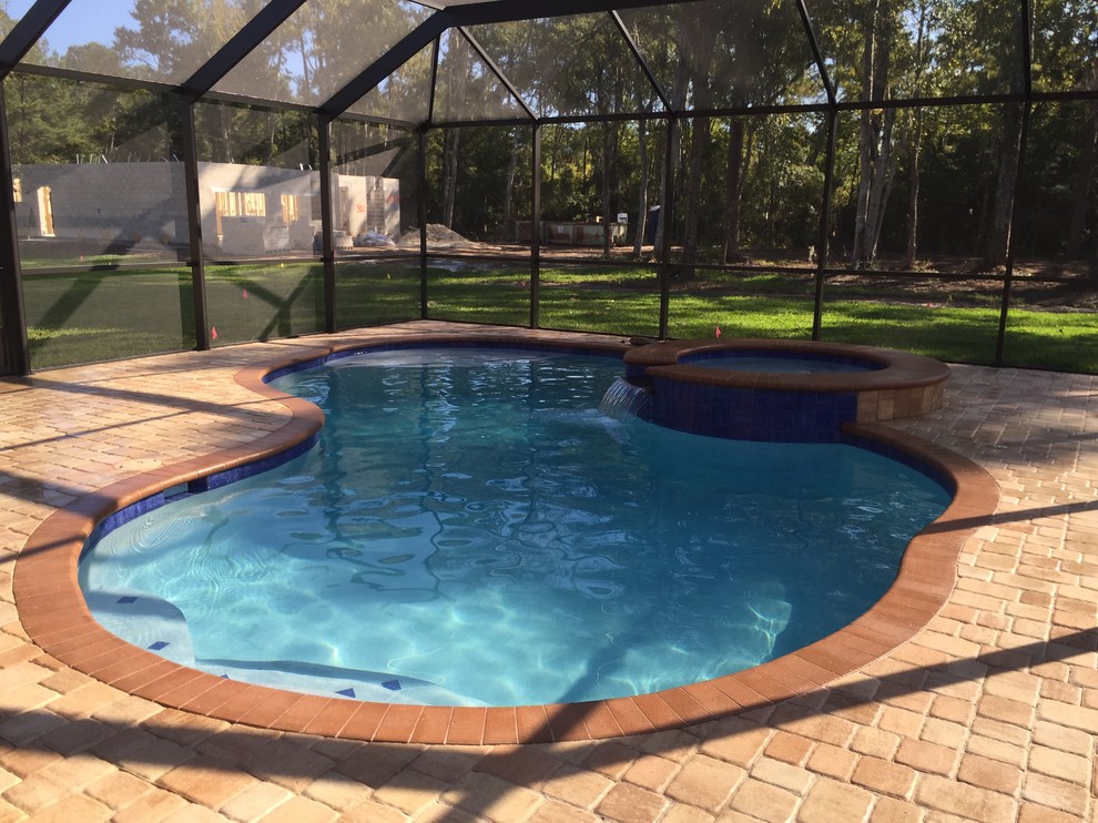 На фото: бассейн произвольной формы, среднего размера на заднем дворе в классическом стиле с мощением клинкерной брусчаткой и джакузи