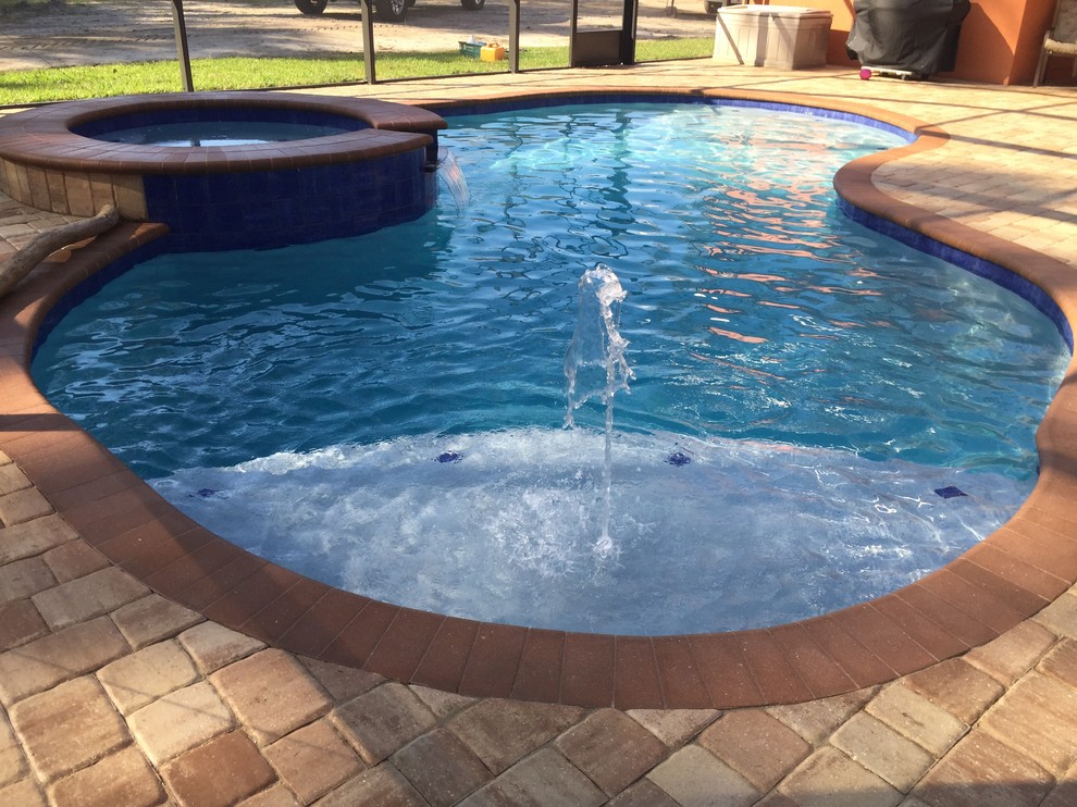 This is an example of a medium sized traditional back custom shaped hot tub in Jacksonville with brick paving.