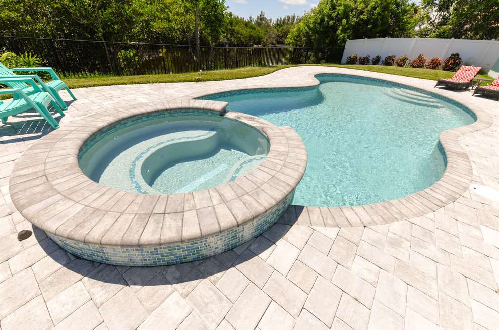 Idee per una piscina contemporanea a "C" di medie dimensioni e dietro casa con una vasca idromassaggio e pavimentazioni in cemento