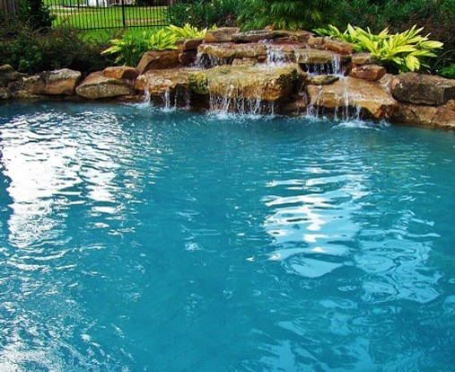 Ejemplo de piscina con fuente moderna grande a medida en patio trasero con suelo de hormigón estampado