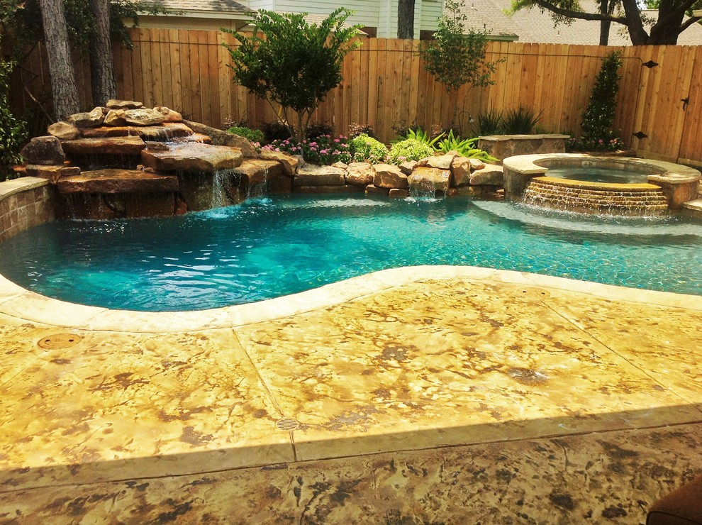 Foto di una grande piscina moderna personalizzata dietro casa con fontane e cemento stampato