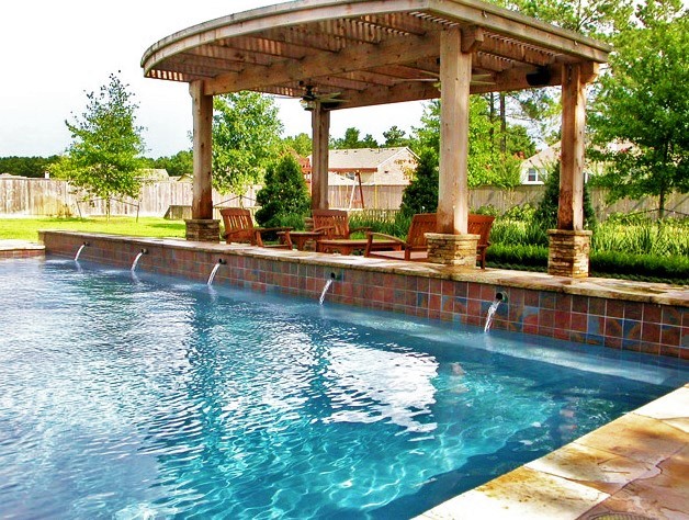Пример оригинального дизайна: большой бассейн произвольной формы на заднем дворе в стиле модернизм с фонтаном и покрытием из декоративного бетона