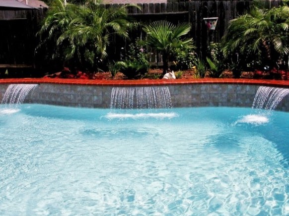 На фото: большой бассейн произвольной формы на заднем дворе в стиле модернизм с фонтаном и покрытием из декоративного бетона