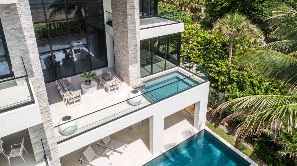 Esempio di una piscina monocorsia minimalista rettangolare di medie dimensioni e dietro casa con una vasca idromassaggio e pavimentazioni in pietra naturale