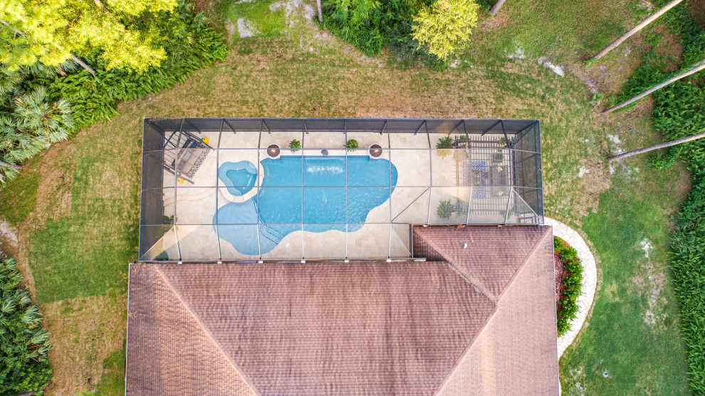 Großer Moderner Schwimmteich hinter dem Haus in individueller Form mit Wasserspiel und Natursteinplatten in Miami