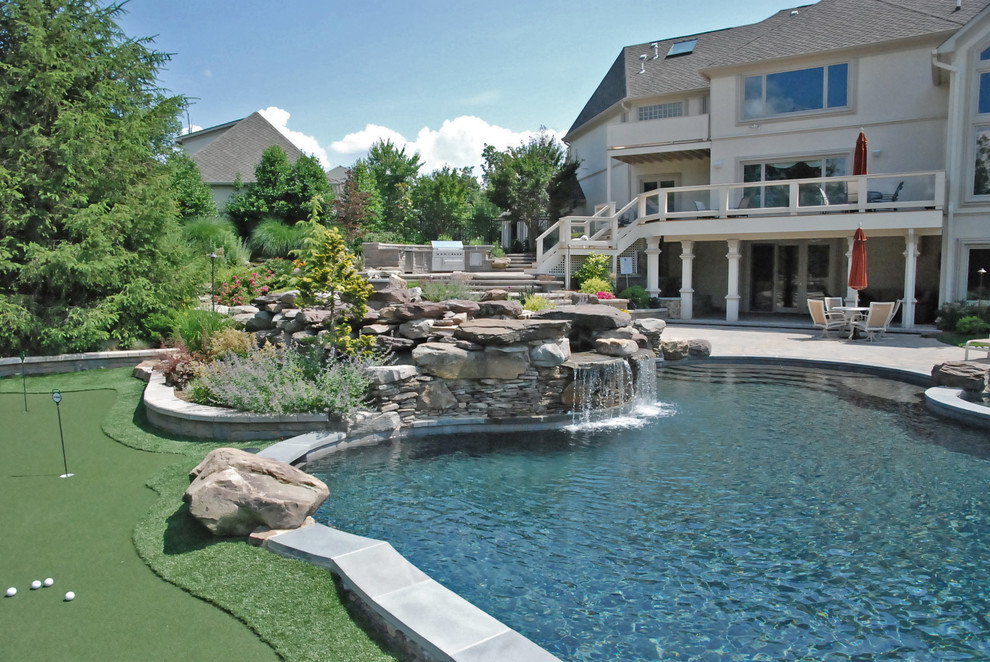 Ispirazione per un'ampia piscina naturale design personalizzata dietro casa con una vasca idromassaggio