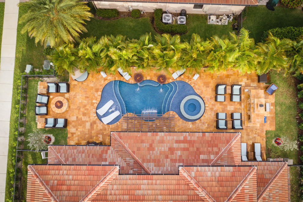 Mittelgroßer Pool hinter dem Haus in individueller Form mit Wasserspiel und Natursteinplatten in Miami