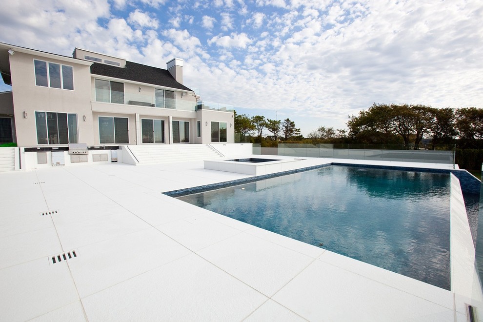 Immagine di un'ampia piscina a sfioro infinito contemporanea rettangolare dietro casa con fontane e piastrelle