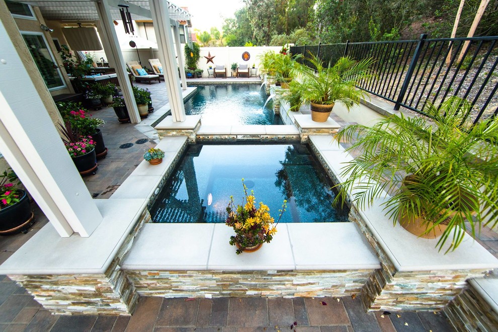 Esempio di una grande piscina monocorsia minimal rettangolare dietro casa con una vasca idromassaggio e pavimentazioni in mattoni