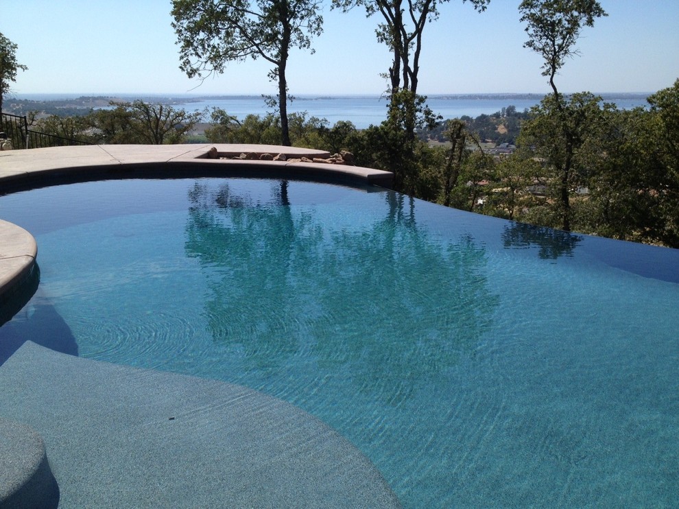 Modelo de piscina infinita mediterránea a medida en patio trasero con losas de hormigón