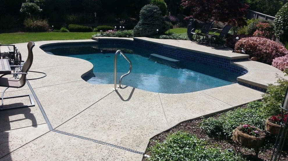 Aménagement d'une piscine arrière classique sur mesure avec une dalle de béton.