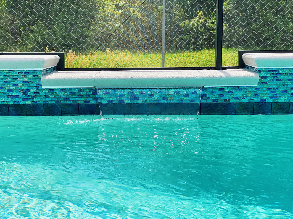 Aménagement d'un piscine avec aménagement paysager arrière de taille moyenne et rectangle avec des pavés en béton.
