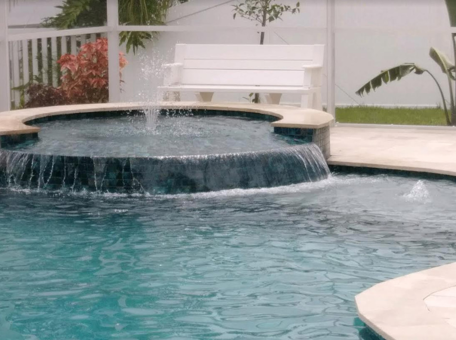 Ejemplo de piscinas y jacuzzis alargados exóticos de tamaño medio en forma de L en patio trasero con adoquines de hormigón