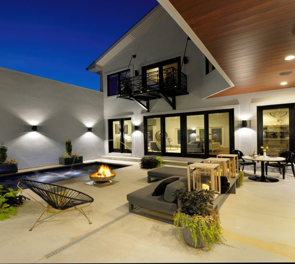 Cette image montre une terrasse arrière minimaliste de taille moyenne avec un point d'eau et une dalle de béton.