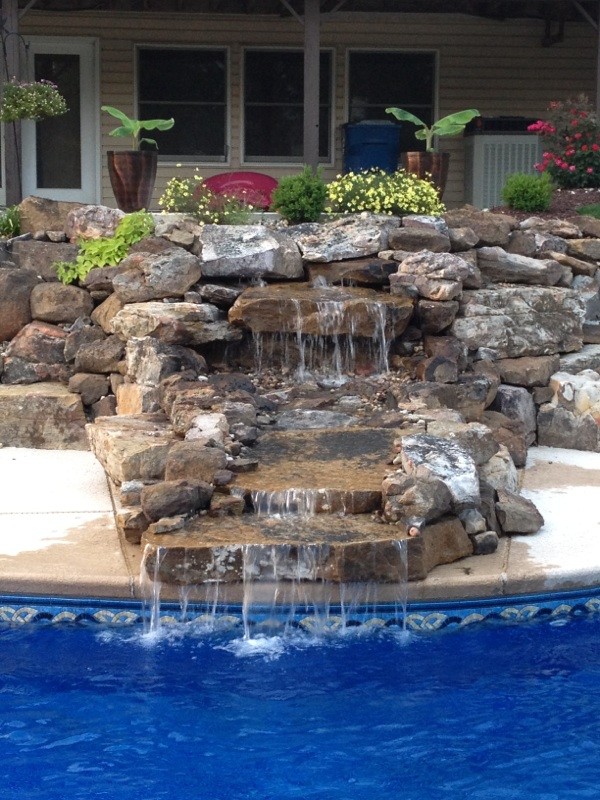 Diseño de piscina con fuente tradicional renovada de tamaño medio a medida en patio trasero con losas de hormigón