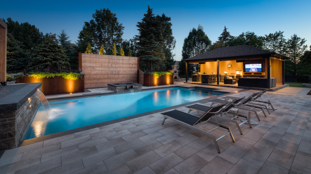 Foto de piscina moderna grande rectangular en patio trasero con adoquines de piedra natural
