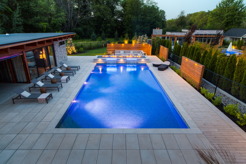 Pool house - large modern backyard stone and rectangular pool house idea in Toronto