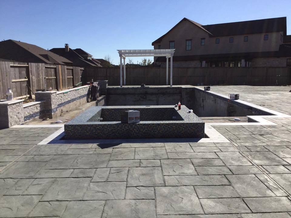 Diseño de piscina clásica grande a medida en patio trasero con suelo de hormigón estampado