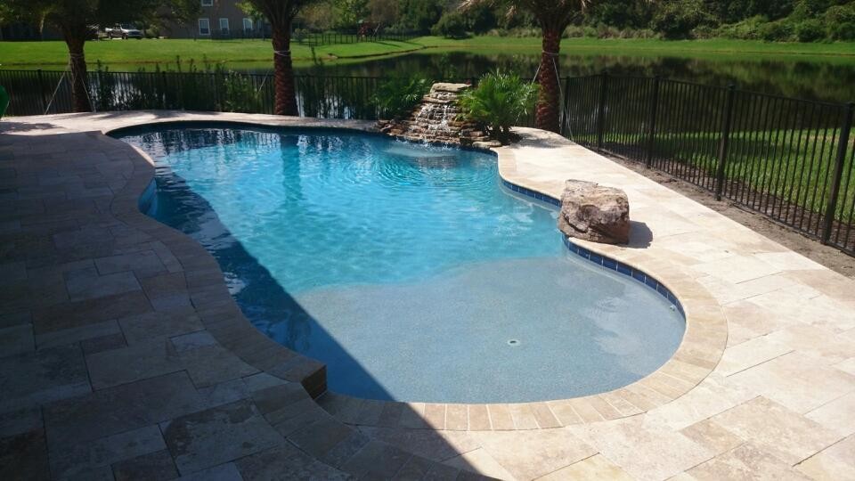 Example of a mid-sized island style backyard stone and custom-shaped natural pool fountain design in Jacksonville