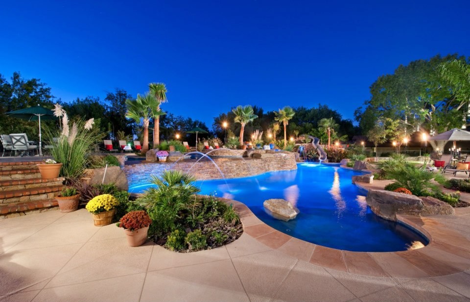 Ispirazione per una grande piscina tradizionale personalizzata dietro casa con fontane e lastre di cemento